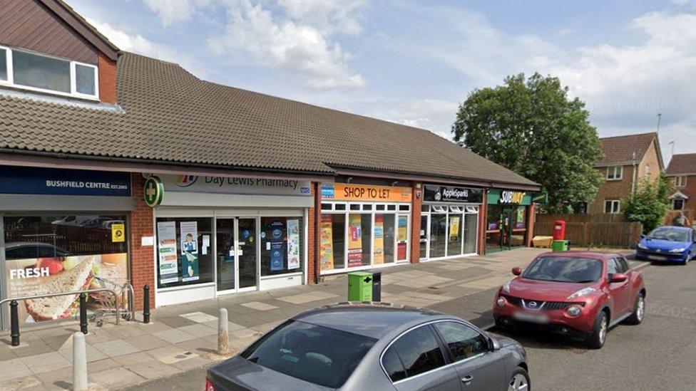 Parade of single-storey shops with cars parked outside