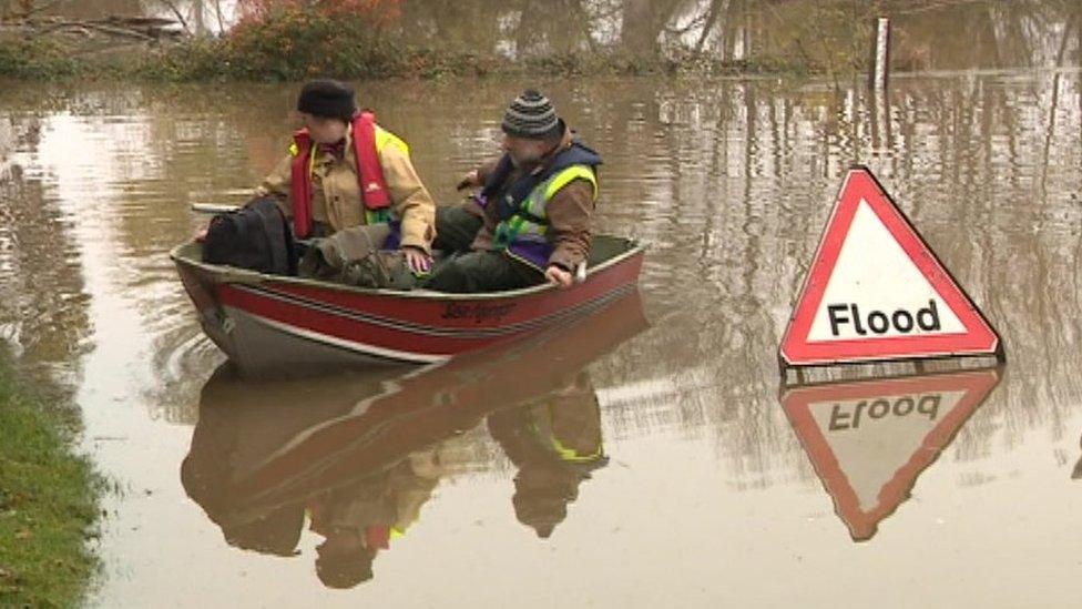 Two people in a boat on a flooded road