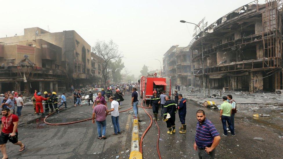 Iraqis, including firefighters, gather at the site of a suicide car bombing claimed by the Islamic State group on July 3, 2016 in Baghdad's central Karrada district