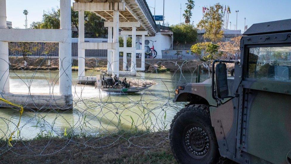 A Customs and Border Patrol boat in the Rio Grande near military vehicles in Eagle Pass in November 2021