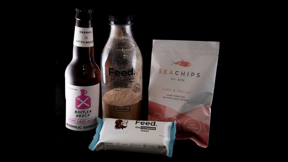 Alcoholic kombucha, a coconut and chocolate meal bar, salmon skin crisps and a powdered chocolate meal drink.