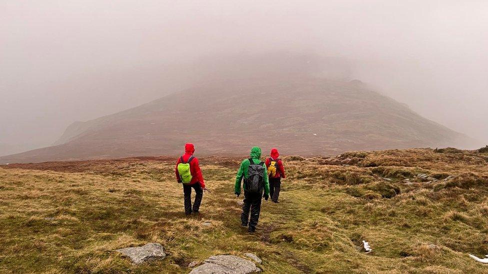 Three volunteers walking on fell in mist