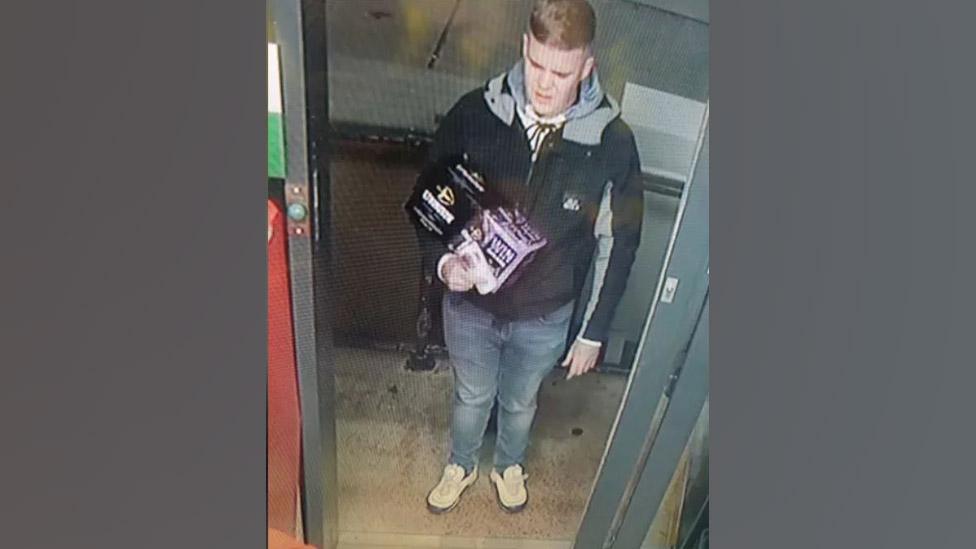 A CCTV image of a man holding beers