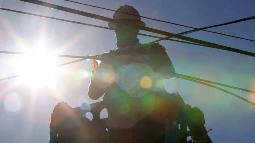 A worker tends to a fibre-optic line in Lake Forest Park, Washington, amid the scorching heat