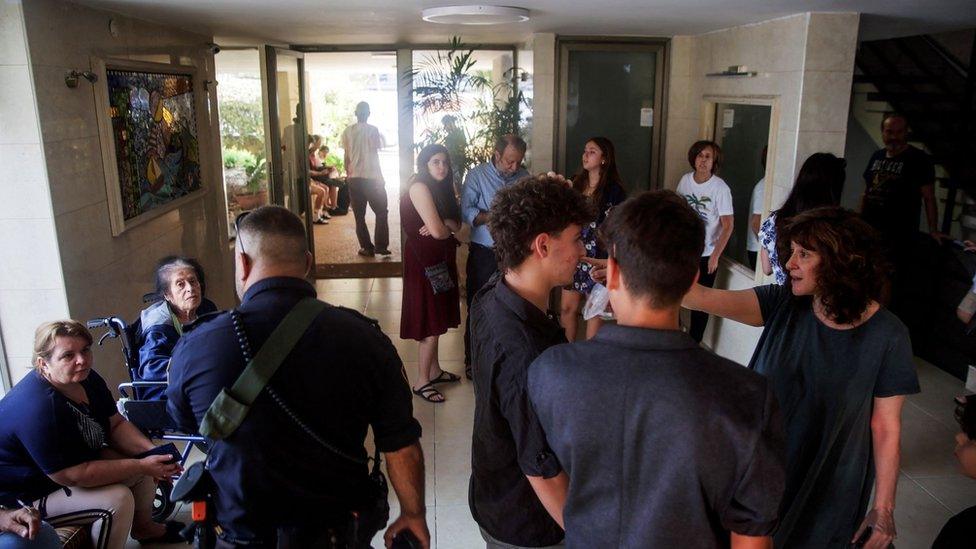 People take shelter in a residential building as rockets are launched from the Gaza Strip, in Tel Aviv, Israel October 7, 2023