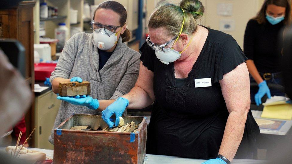 Conservators with the Virginia Department of Historic Resources, remove items found in a time capsule.