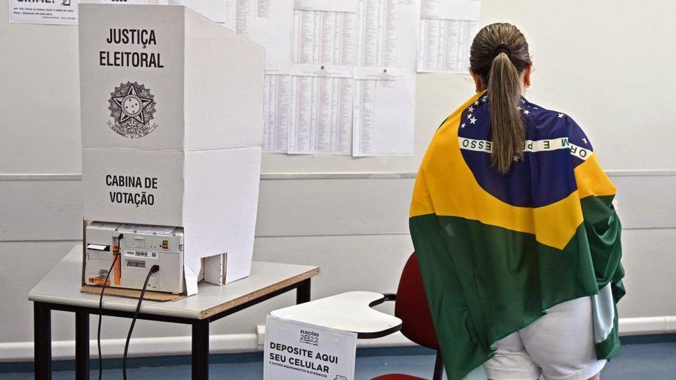 A woman wrapped in a Brazilian flag votes at a polling station in Brasilia