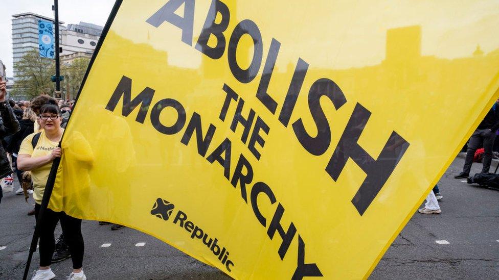 Protestor holding a sign that reads "Abolish the Monarchy"