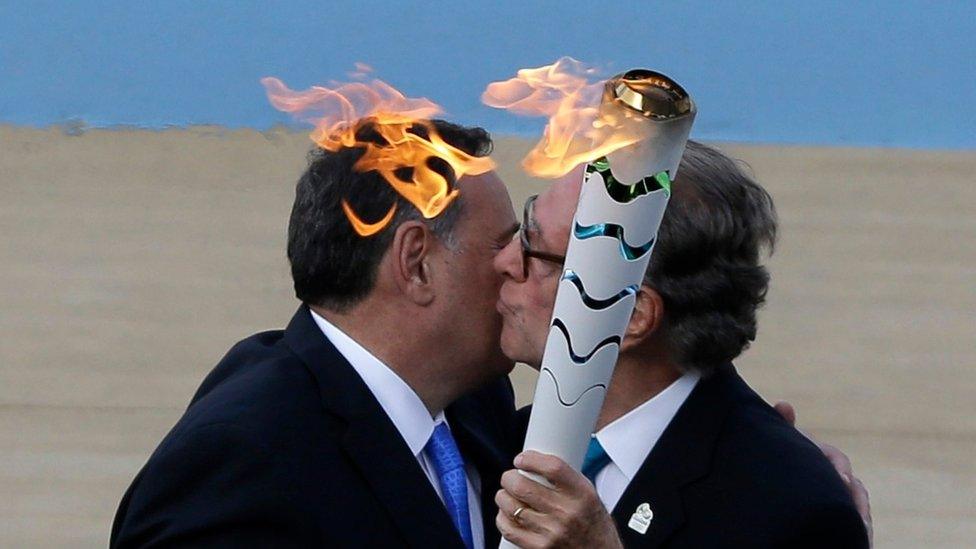 Carlos Nuzman, right, receives a torch with the Olympic Flame