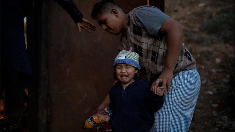 A migrant girl from Honduras cries as a group of migrants tries to jump a border fence to cross illegally from Mexico to the US on 2 December, 2018