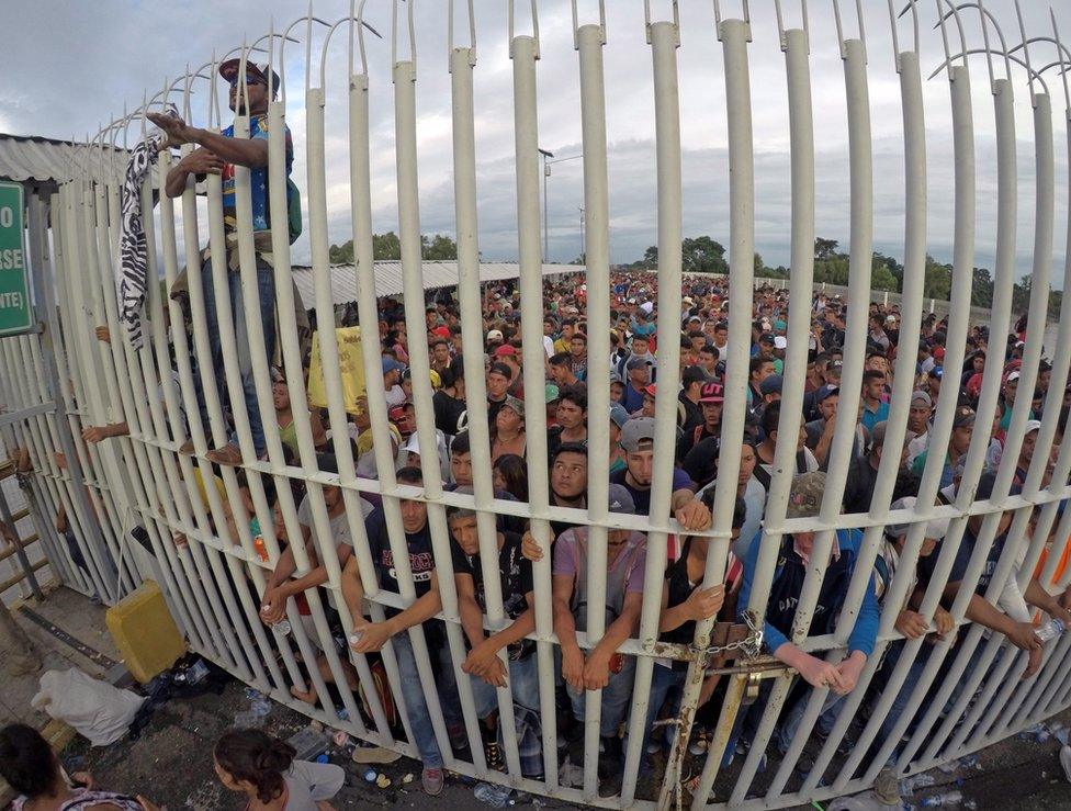 Honduran migrants wait behind a gate after crossing the fence on the border with Guatemala to enter Mexico