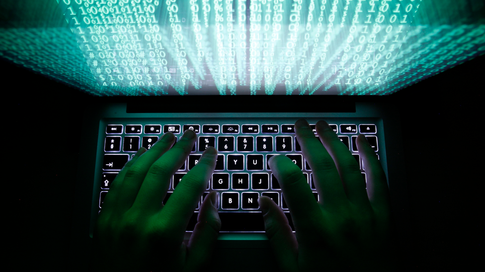 A man types on a computer keyboard