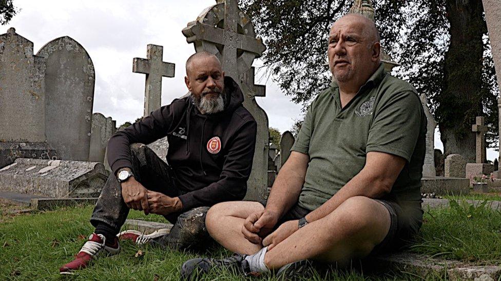 Two men sitting in a graveyard