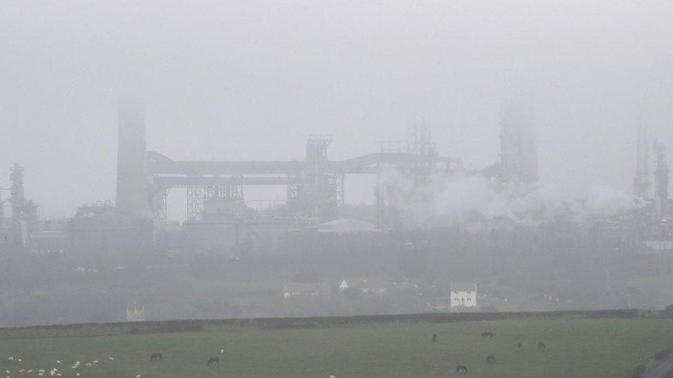 Fog engulfs the towers of the oil refinery in Pembroke, Wales