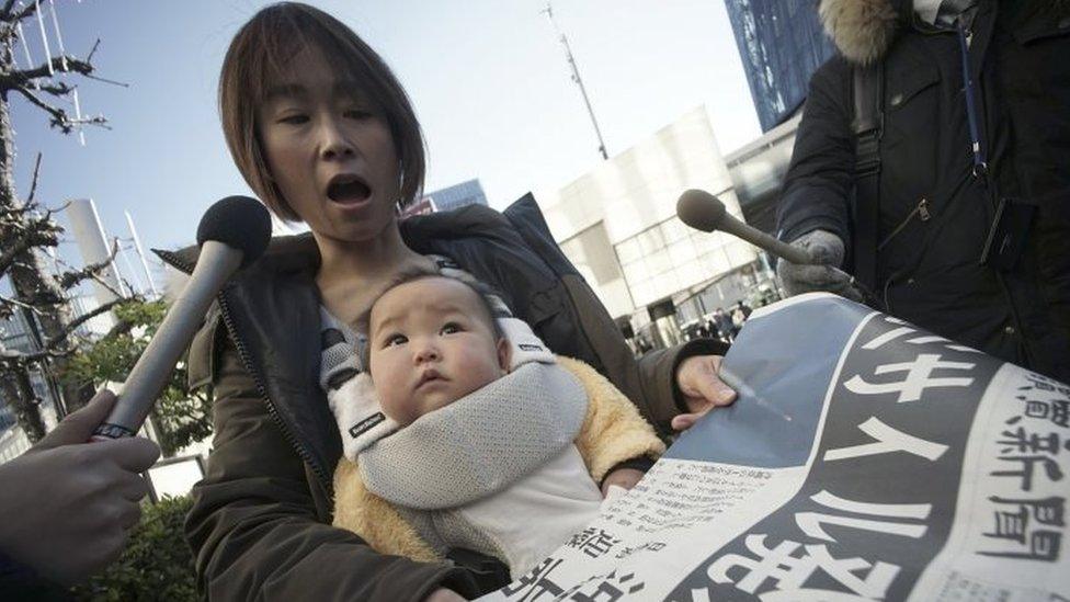 A woman buys a newspaper reporting North Korea's rocket launch in Tokyo (07 February 2016)