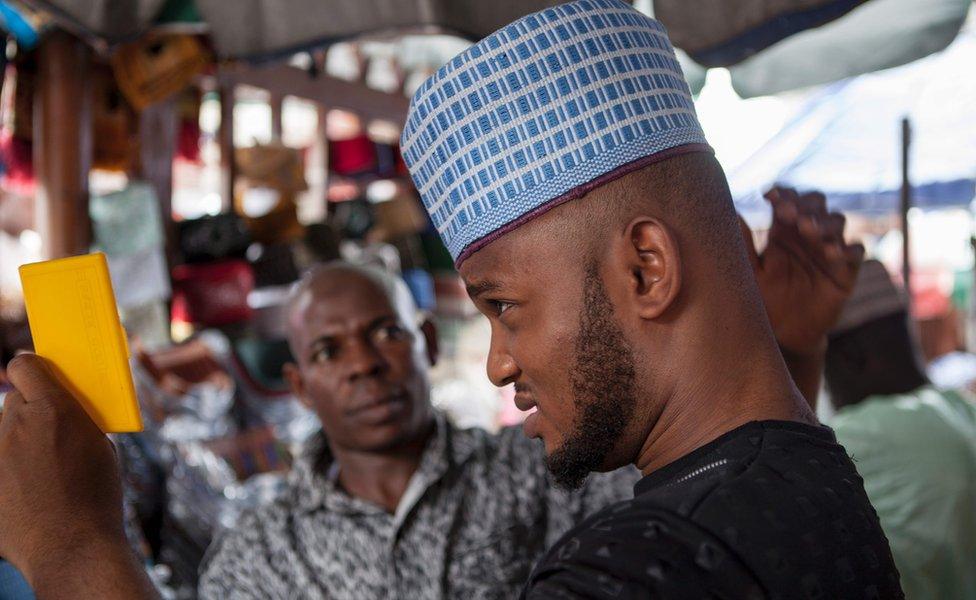 A man tries on a traditional Nigerian cap at the entrance of the Central Mosque in Lagos on July 5, 2016 during public holidays marking the end of the Muslim holy month of Ramadan