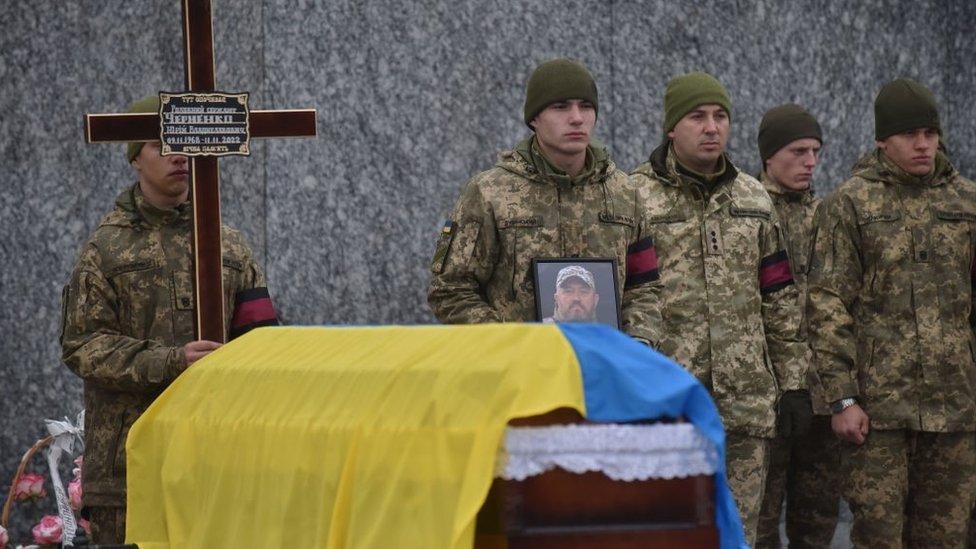 A coffin and grieving soldiers