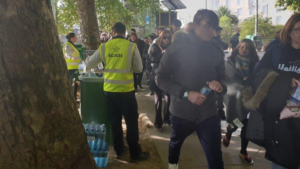 Scouts handing out water to people in the queue