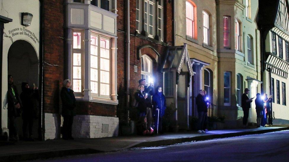 People light up their cell phones while they stand outside, as part of a day of reflection to mark the anniversary of Britain's first coronavirus disease (COVID-19) lockdown, in Lichfield, Britain March 23, 2021