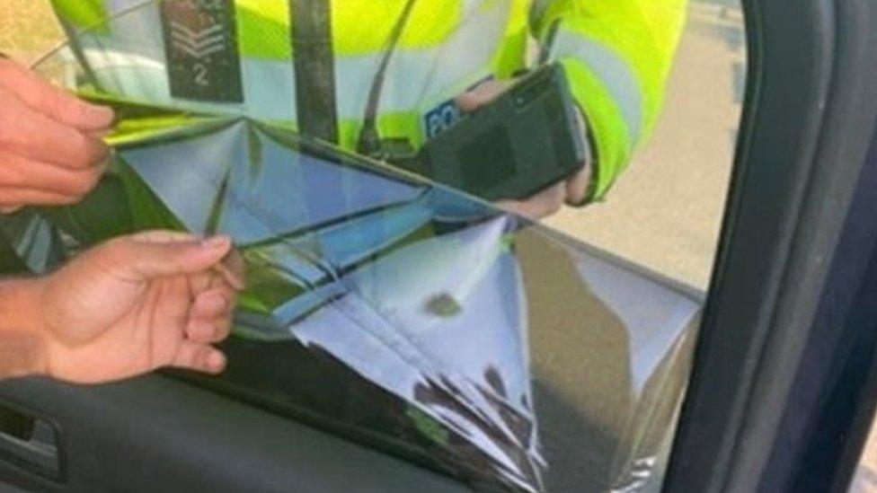 Police officers taking a blackout film off a vehicle