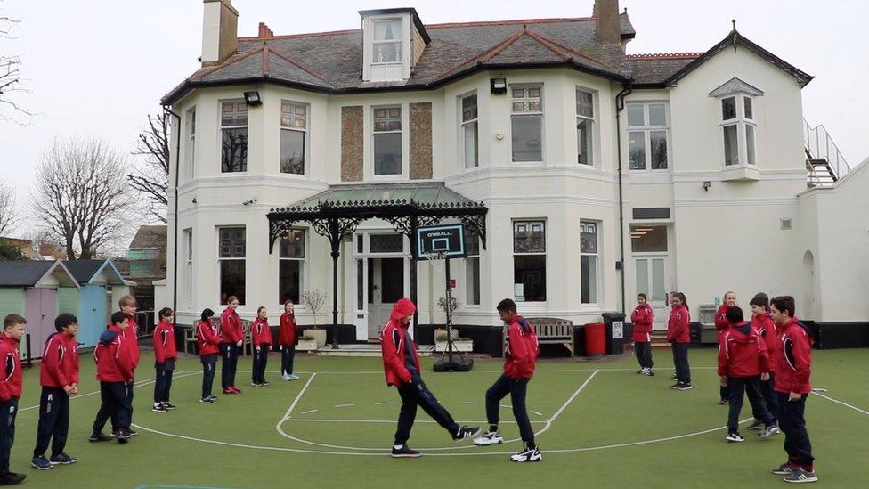 Pupils greet each other with a foot-to-foot tap instead of shaking hands to avoid the spread of coronavirus, in Hove, Britain