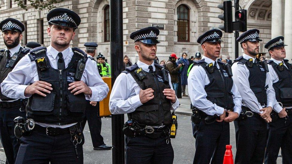 Police officers standing in a row in the middle of a road