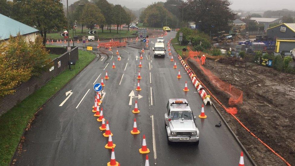 Cars driving through lanes off the roundabout lined with traffic cones