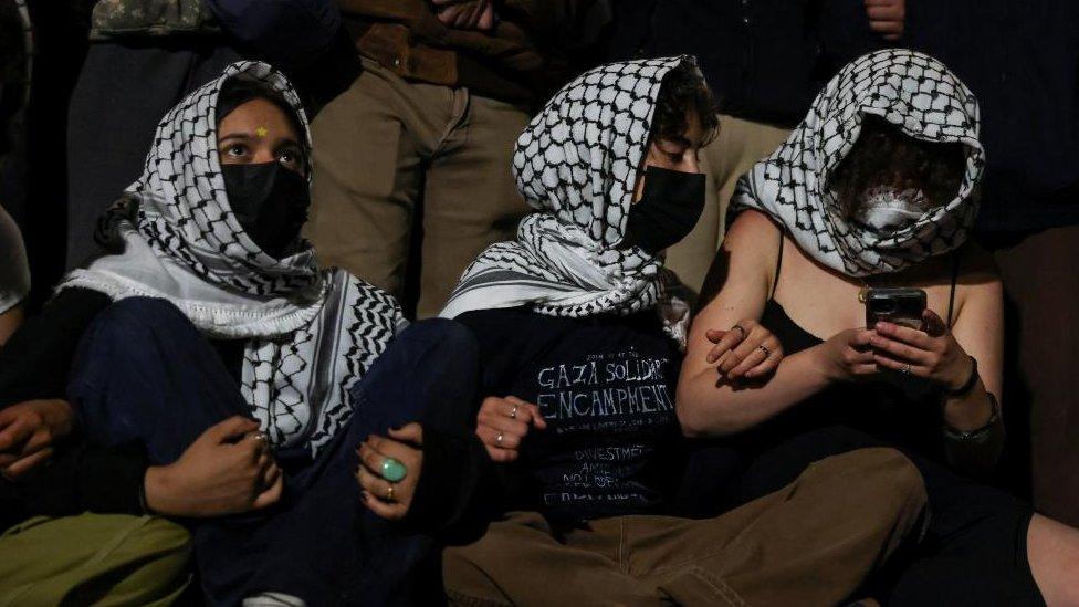 Three protesters link arms outside Hamilton Hall at Columbia University