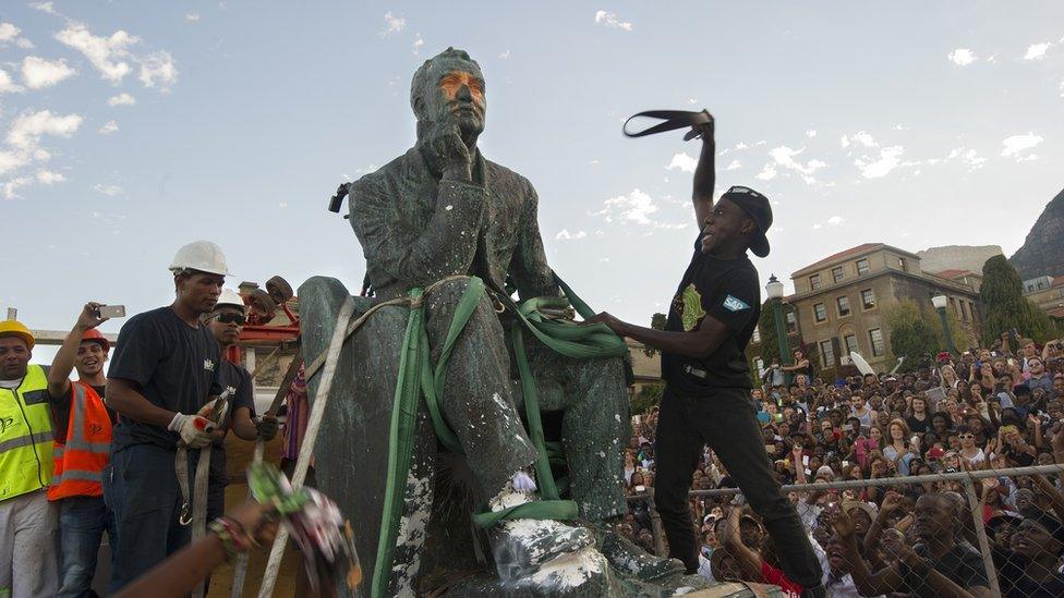 Students attack the defaced statue of British mining magnate and politician, Cecil John Rhodes, as it is removed by a crane from its position at the University of Cape Town on 9 April 2015