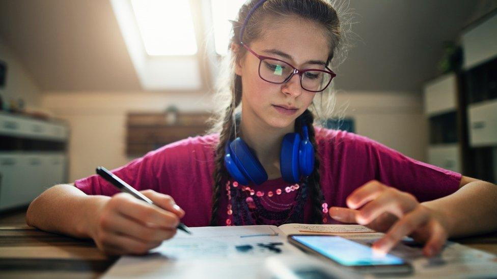 Girl doing school work with mobile