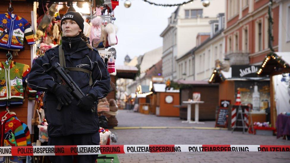 A police officer stands guard behind a police line at the otherwise bustling Potsdam Christmas market, now empty after it was evacuated by police, Potsdam, Germany, 01 December 2017.