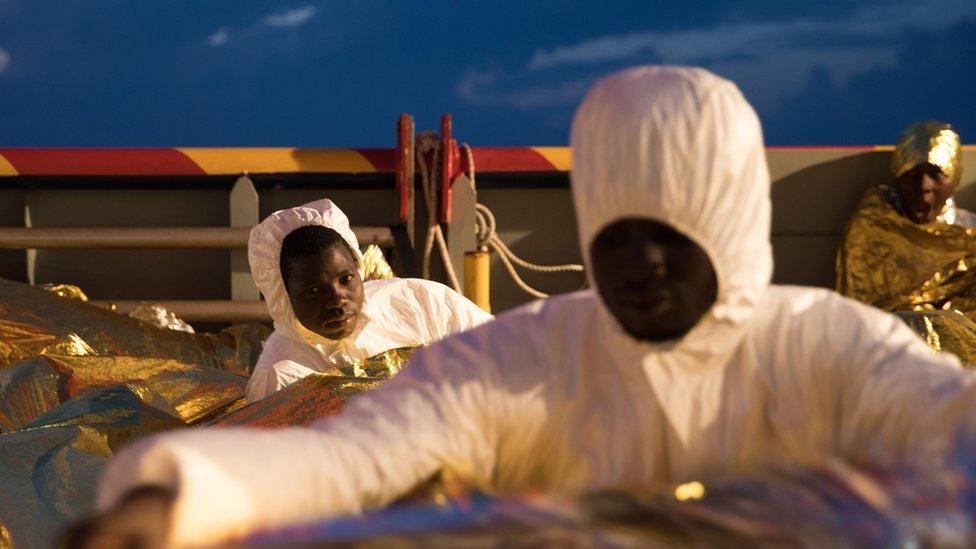 Men wearing rain ponchos are pictured, with many others hidden under gold survival blankets on a boat in the Mediterranean - Wednesday 23 November 2016