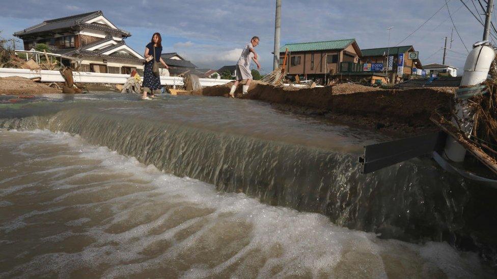 Residents cross an area still flooded in Kurashiki, Okayama prefecture on July 9, 2018