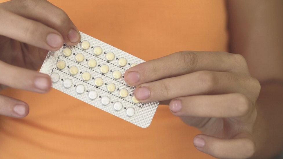 Woman holding oral contraceptive pills