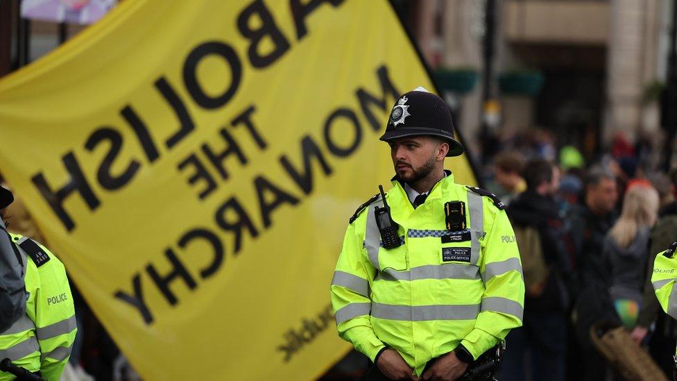 A police officer watches members of the anti-monarchy group Republic protesting