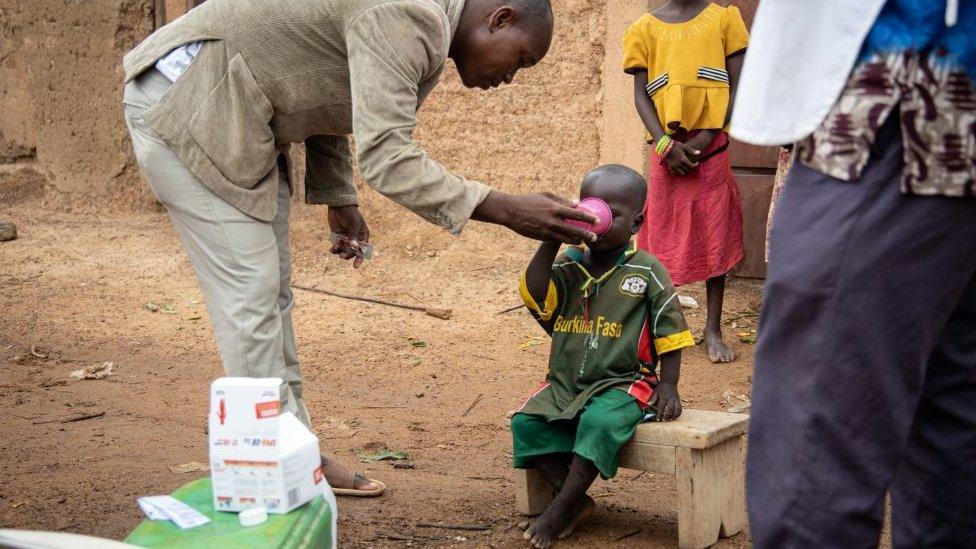 boy takes drink from doctor in Burkina Faso.