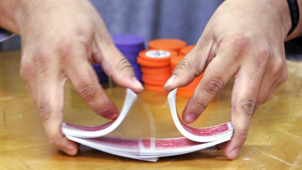 hands mixing poker cards, with chips in the background