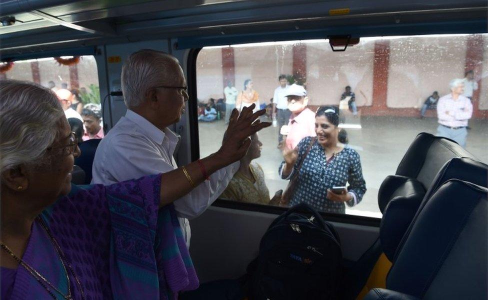 In this photograph taken on May 22, 2017, Indian passengers wave to relatives onboard the Tejas Express luxury train during its first journey between Mumbai and Goa in Mumbai.