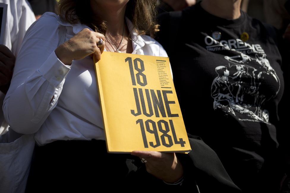 Protester holds card reading "18 June 1984"