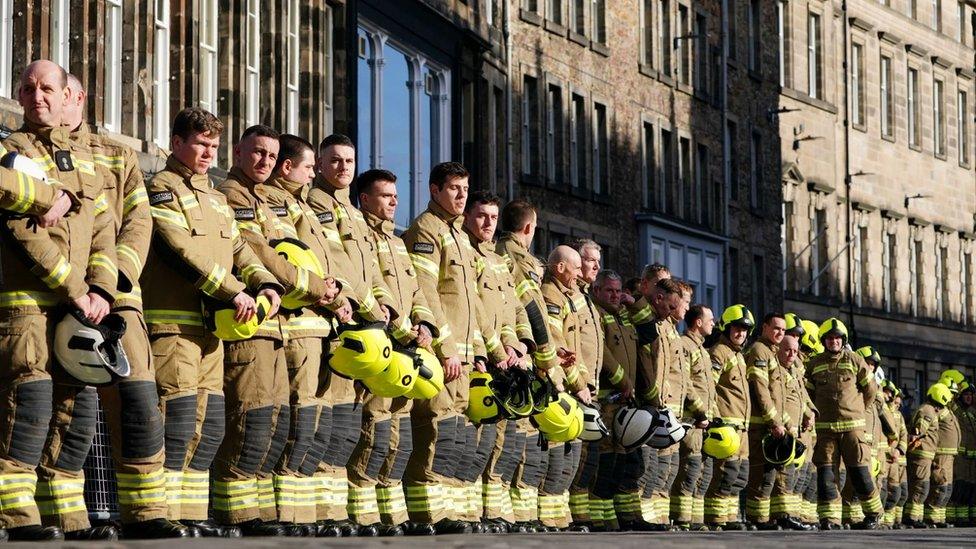 Firefighters line the street