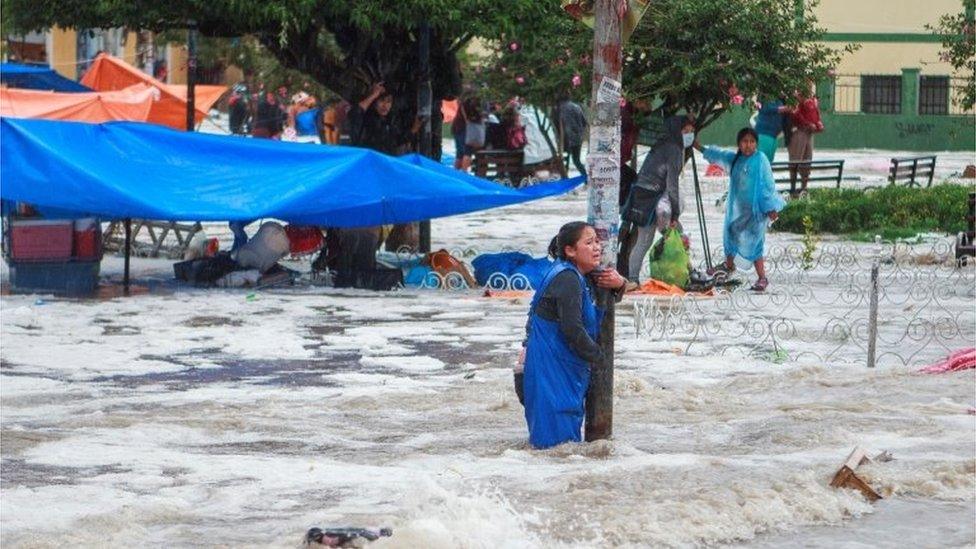 A woman clings to a lamp post during flooding caused by heavy rains in Sucre, Bolivia January 4, 2021