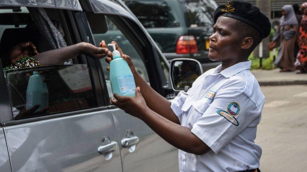 A security officer dispenses chlorinated water to a passenger at Muhimbili National Hospital in Dar es Salaam