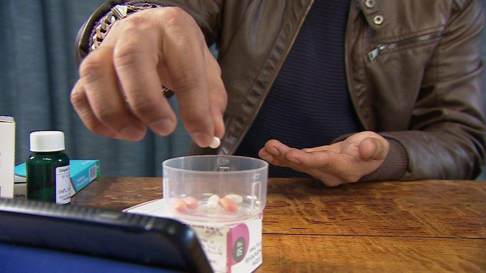 A hand dropping pills into a cup