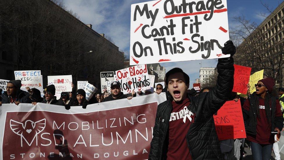 Michael J. Weissman, 18, a student at Marjory Stoneman Douglas, where a mass shooting occurred last February 14 that left 17 dead, carries a sign as he and other participants hold the "March for Our Lives" event