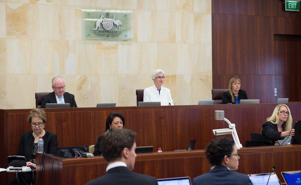 Wide shot of the Commission during a hearing in October 2015, showing Commissioner Robert Fitzgerald (left), Justice Jennifer Coate (centre) and Commissioner Helen Milroy (right), with three other women seated in the row in front of them. Image supplied by Royal Commission Media, taken 6 October 2015 in Adelaide.