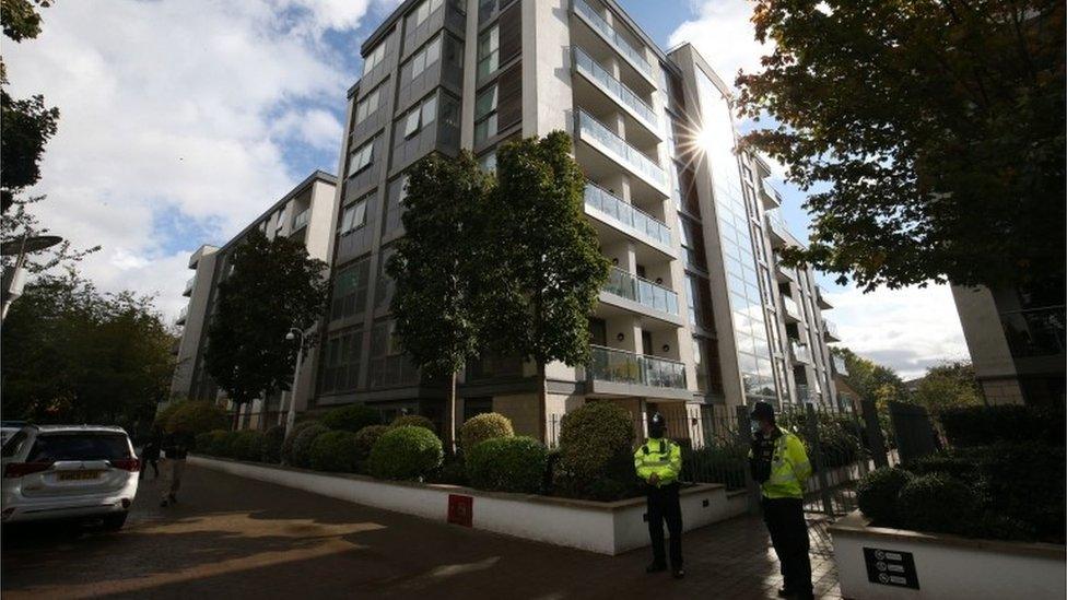 Police officers stand outside a block of flats where a boy and two adults died