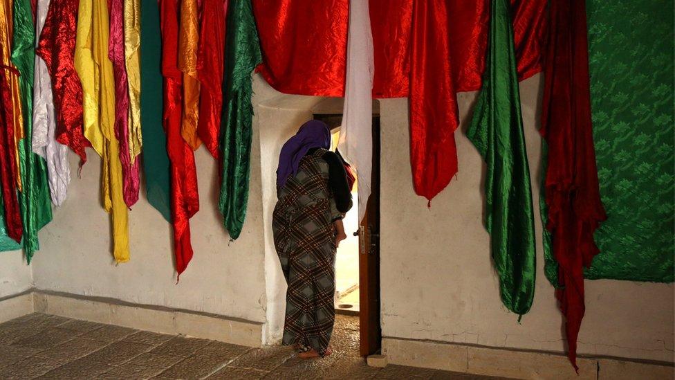 A Yazidi woman walks out of the Sharaf Al-Deen temple in Shingal"s outskirts, Iraq, August 14, 2016