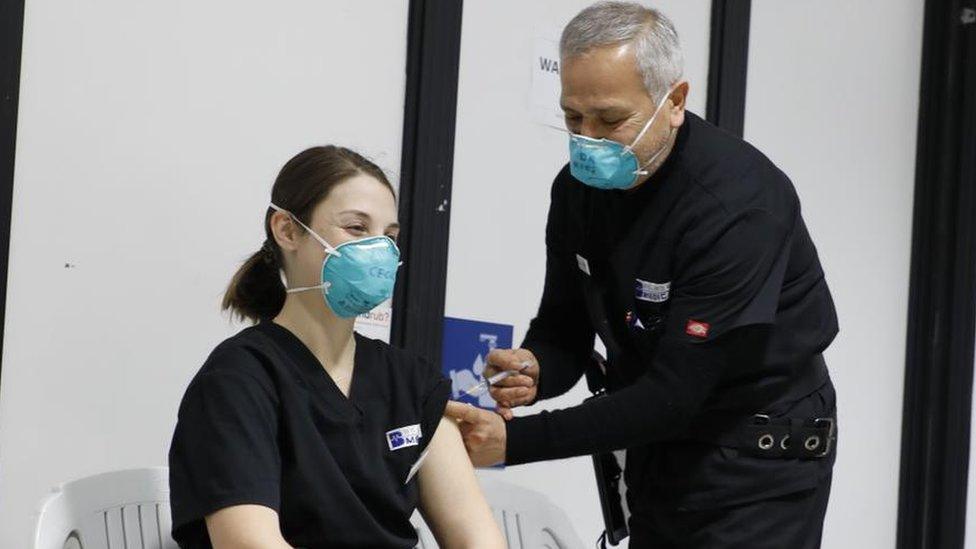 Dr Jamal Rifi gives a vaccine shot to a fellow health worker