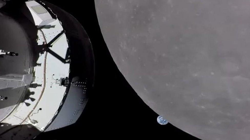 Earth in the background, with the moon, and Orion spacecraft