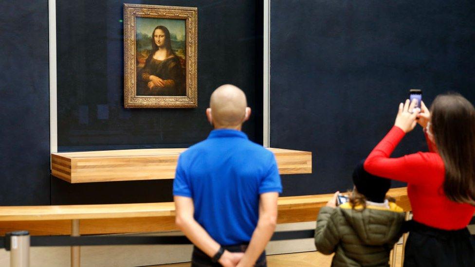 Tourists look at the Mona Lisa